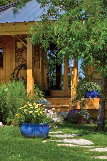 Clematis covers the entryway trellis. Denise plants flowers that attract hummingbirds to the pots on the porch.